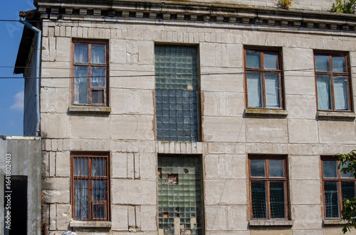 A large building with many windows and a large window in the middle. The building is old and has a lot of damage