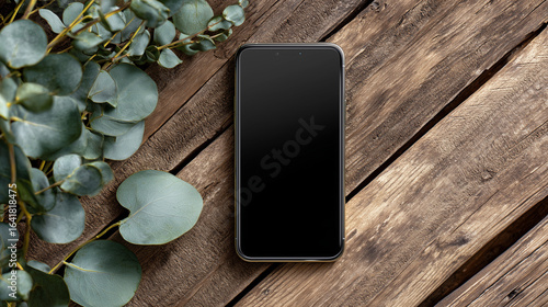  Flat Lay of iPhone 16 Pro Max with Black Screen on a Rustic Wooden Table with Eucalyptus Leaves