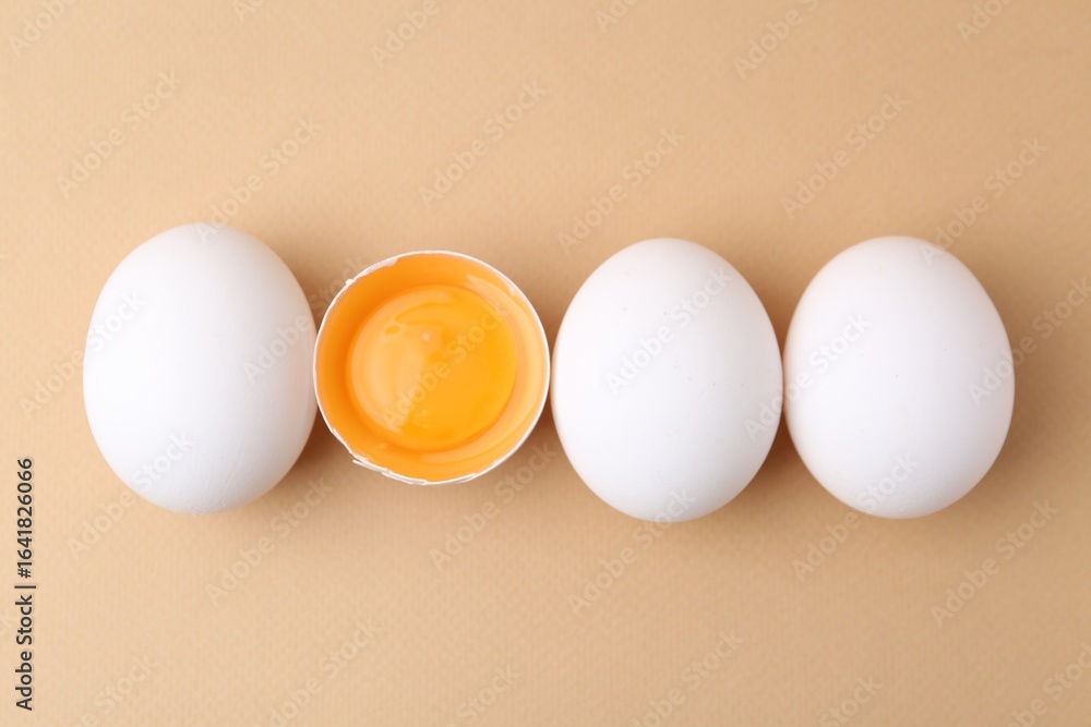 Fototapeta premium Whole and broken chicken eggs on beige background, top view