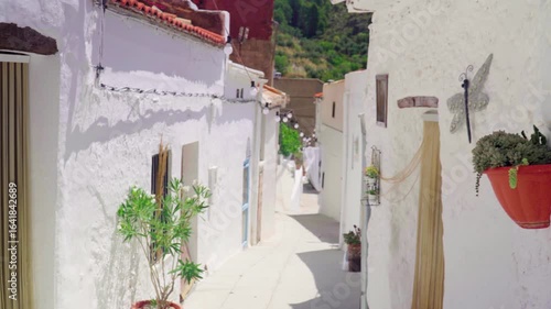 Old street decorated with flowers, white houses and plants, in Molinicos village, Castilla la Mancha, Spain.