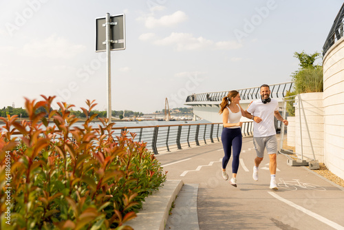 Couple enjoying a lively run along a scenic waterfront path in summer