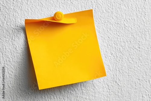 Bright yellow sticky note affixed to a light gray wall