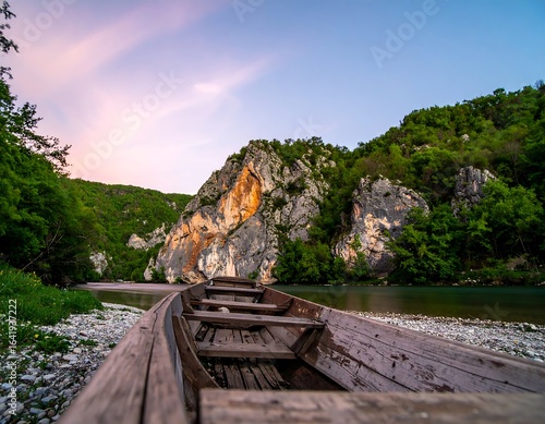 Wooden boat on river, mountains at sunset