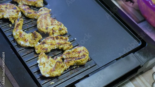 cooking chicken fillet on an electric grill at home
