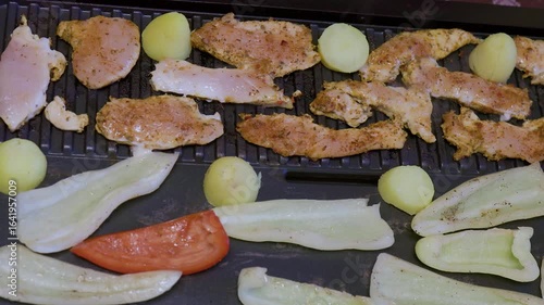 cooking chicken fillet with vegetables on an electric grill at home