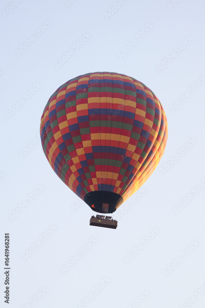 Obraz premium Multicolored Hot Air Balloon with Checkered Pattern Floating in Clear Morning Sky