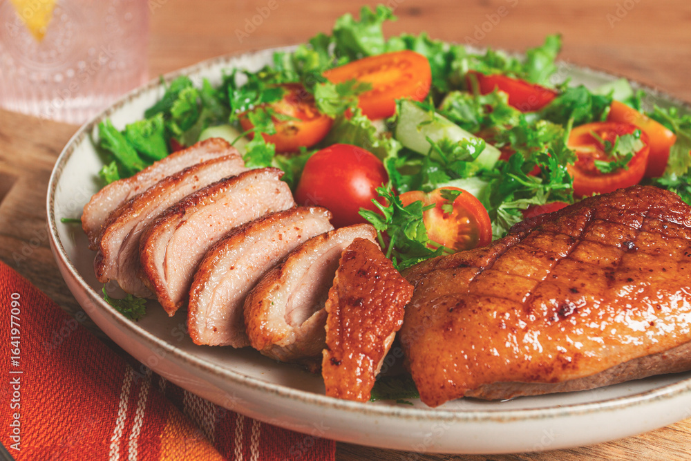 Delicious grilled duck breast served with fresh garden salad and cherry tomatoes at a rustic dining table Delicious grilled duck breast served with fresh garden salad and cherry tomatoes at a rustic dining table