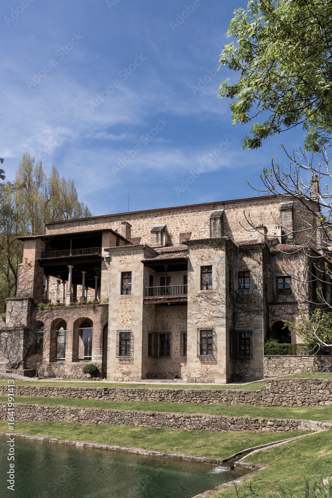 Obraz premium Medieval spanish castle overlooking tranquil pond on sunny day
