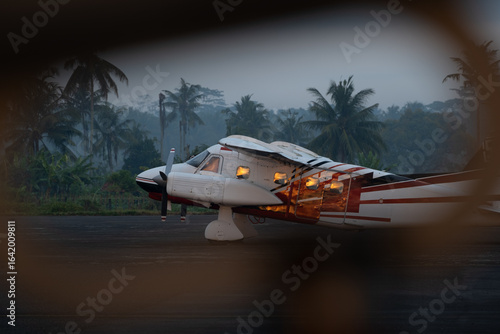 Small twin-engine piston aircraft on tarmac at dawn, framed view