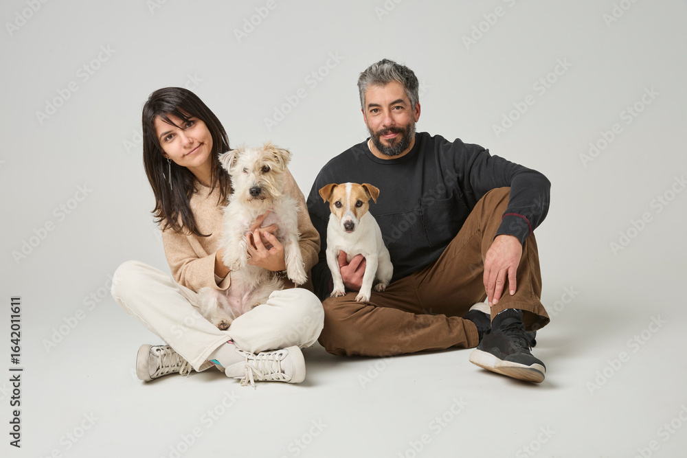 Φωτογραφία Couple sitting on floor with their two pet dogs in studio, concept of modern fam