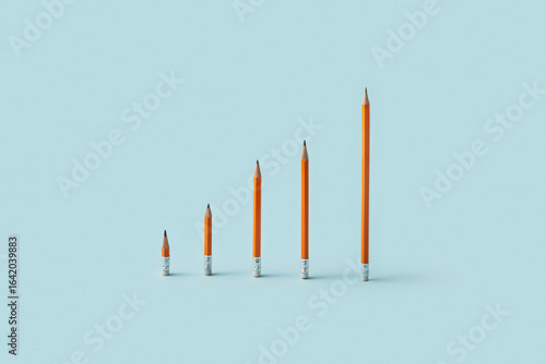 Orange pencils arranged as ascending bar graph on blue