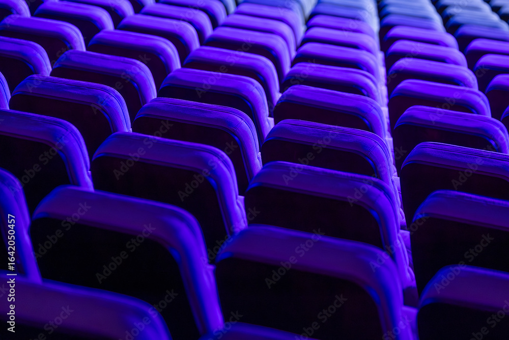 Obraz premium Brightly lit rows of theater chairs in vivid blue hues creating a dynamic abstract scene
