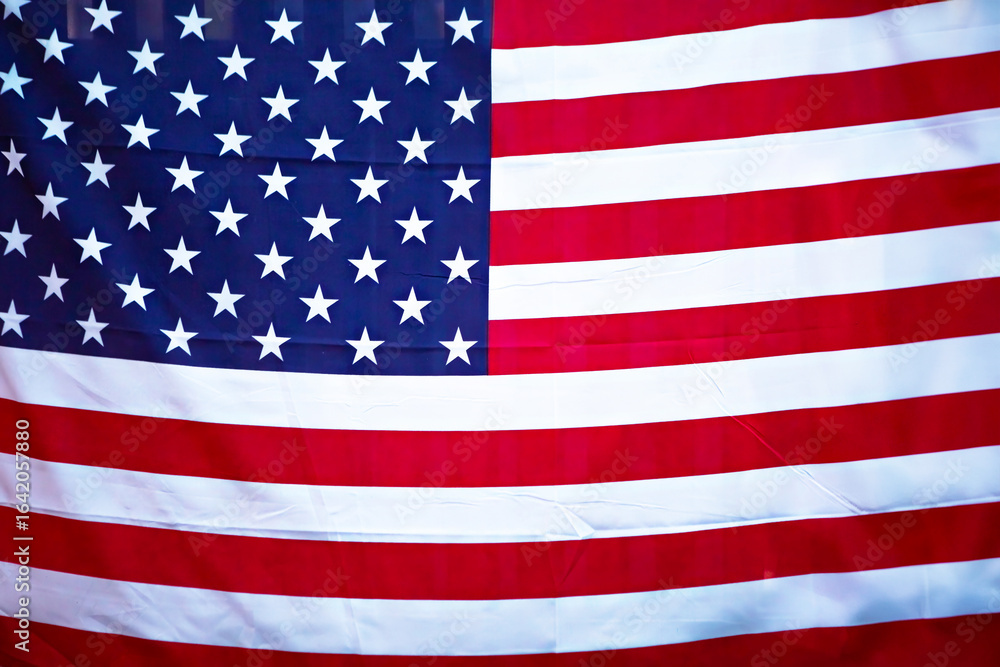 Fototapeta premium Closeup of a waving American flag mounted on a building with a blue sky in the background