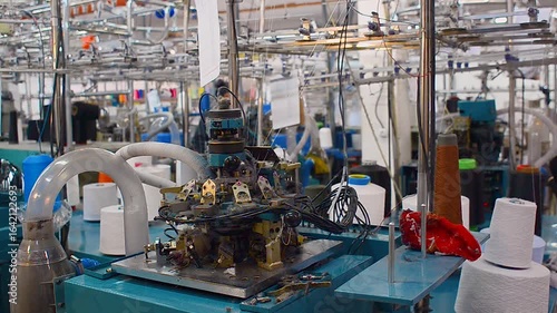 Workshop with row of blue knitting machines in textile factory, designed for production of socks