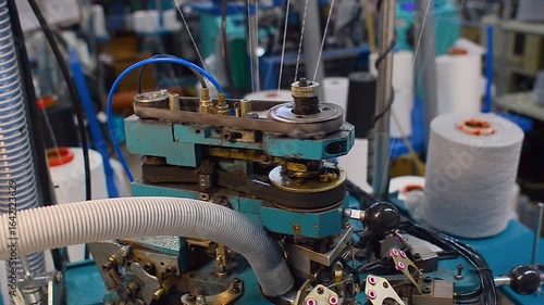 Detailed process of making socks on loom. Video close-up of white threads on rewinding machine.