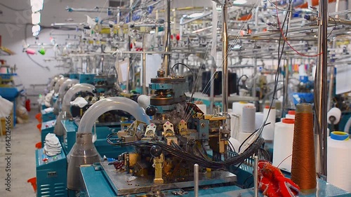 Workshop with row of blue knitting machines in textile factory, designed for production of socks