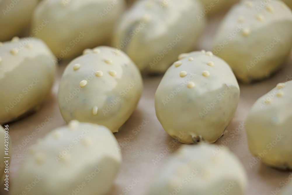 Fototapeta premium White chocolate potato covered pastries with nut decoration in bakery factory
