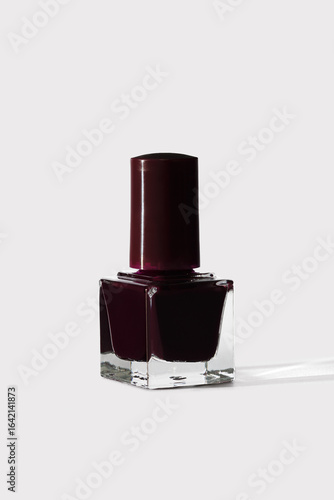 Deep burgundy nail polish in a clear bottle on white