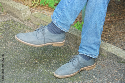 two blue suede boots on legs in jeans on gray ground on autumn street