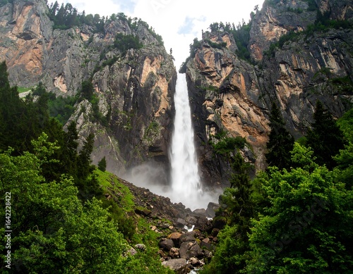 Majestic waterfall cascading down rocky mountain face, surrounded by lush forest