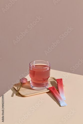 Glass of Rose-Colored Drink on Wooden Tray With Stirrer and Sachets