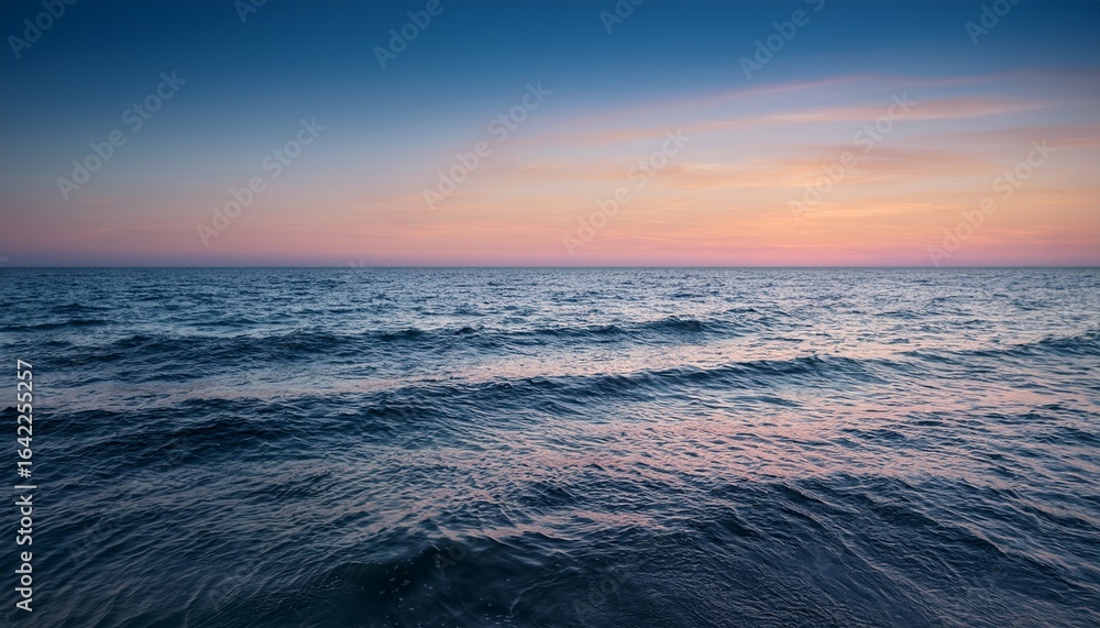 Obraz premium calm ocean sunset horizon with gentle waves and pastel sky colors creating a serene atmosphere for relaxation and nature lovers coastal landscape photography