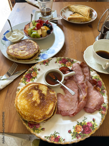 Wallpaper Mural Delicious english breakfast plate featuring fluffy pancakes and crispy bacon served with maple syrup on a decorative floral plate, showcasing a delightful morning meal experience. Vertical background Torontodigital.ca