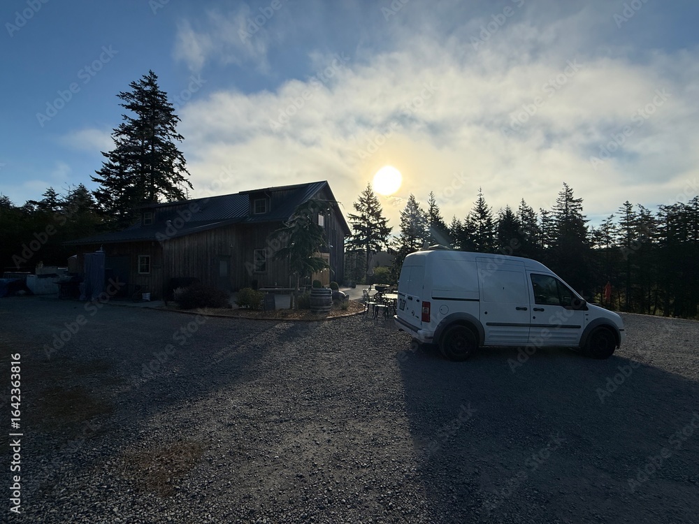 Fototapeta premium Barn-style building and white van at sunset