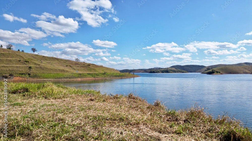 Impressionante paisagem aérea de barragem rodeada por colinas verdes e céu azul, perfeita para projetos turísticos e naturais. Impressionante paisagem aérea de barragem rodeada por colinas verdes e céu azul, perfeita para projetos turísticos e naturais.