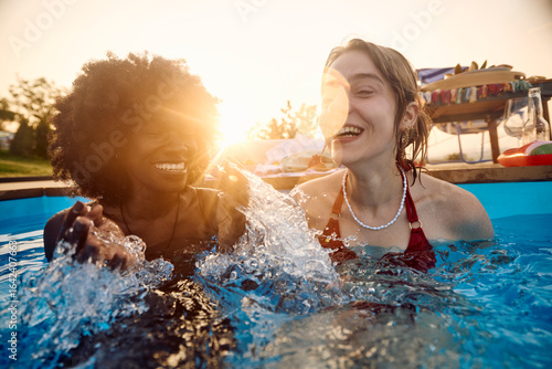 Women are having fun in the pool at sunset