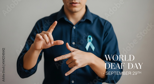 A person signing with hands wearing a blue shirt and a ribbon for world deaf day september twenty ninth