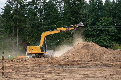 Foto Earthworks phase of new home construction project, excavator digging up dirt, an