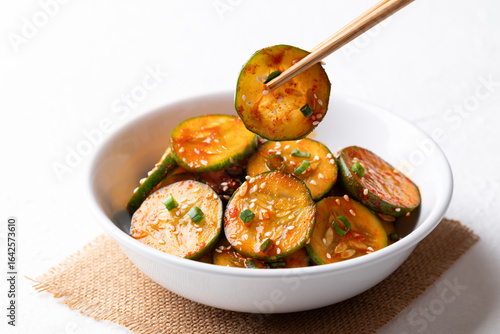 Bild auf Leinwand Korean cucumber salad (Oi muchim) in bowl with chopsticks on white background, K