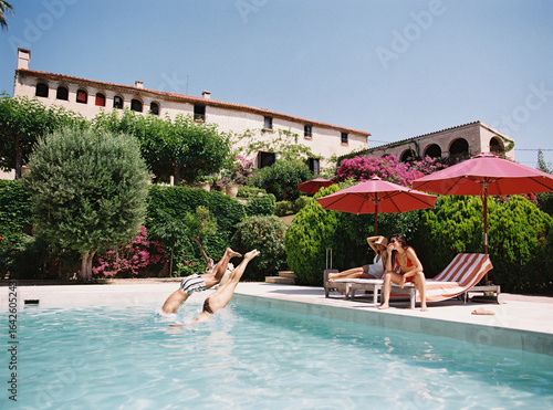Friends diving into swimming pool at luxury hotel resort