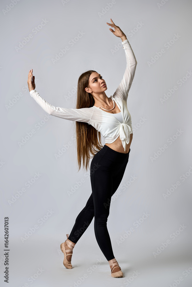 Fototapeta premium A woman in a white shirt and black pants is dancing