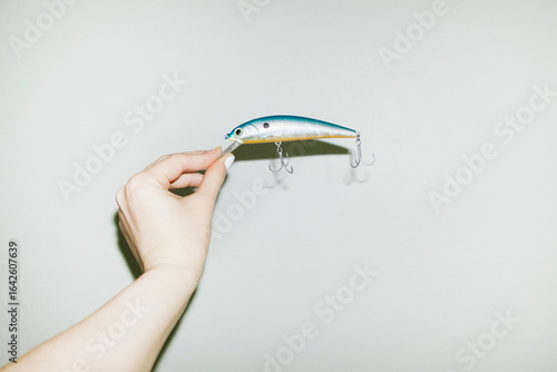 Hand holding fishing equipment lure with hard direct flashlight
