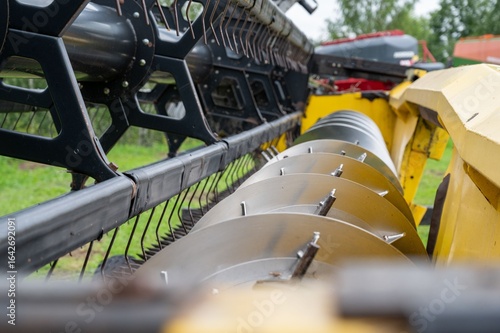 Canvas-taulu Close-up of agricultural machinery with metal blades and green field background