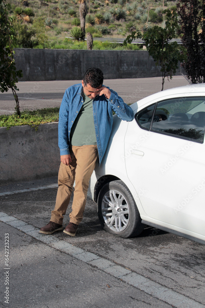 Adult Latino dark-skinned man suffers a car accident and has a flat tire and has to change it Adult Latino dark-skinned man suffers a car accident and has a flat tire and has to change it