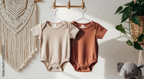 Two Infant Bodysuits, Beige and Terracotta, Hang on Wooden Rack