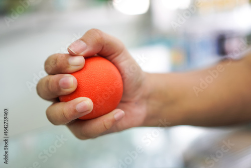 Close-Up of Hand Squeezing Red Stress Ball for Therapy