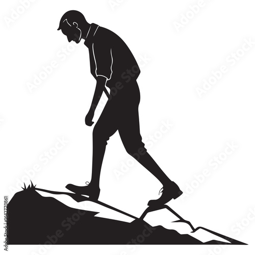 A lone figure in a striking black silhouette walks determinedly uphill on a rocky uneven terrain conveying a sense of perseverance and challenging journey silhouette