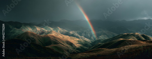 A vivid rainbow arcs across the stormy sky, casting a beautiful spectrum of light over the expansive mountain landscape