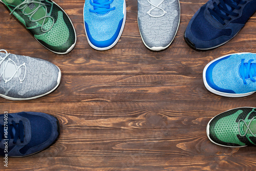 Top view shop display of unbranded modern new stylish sneakers running shoes for men on wooden background texture with copy space.