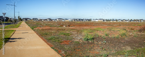 Foto A large vacant lot in a developing suburban neighborhood of Aintree, an outer suburb of Melbourne, with modern new houses in the distance
