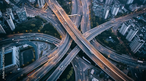 Aerial view of a complex highway interchange at night, with city buildings surrounding it