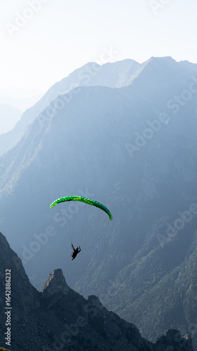 A speedglider (paraglider) launching off into the mountains