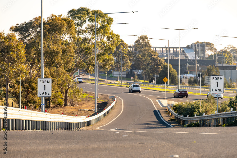 Fototapeta premium Freeway merge entrance with “Form 1 Lane” signs, guardrails in suburban Melbourne, Australia. Concept of transport infrastructure, highway entry and commuting