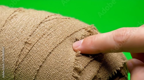 Finger Poking Hole in Mummy Bandages - Close-up shot of a finger slowly poking a hole through aged, tan linen mummy bandages.