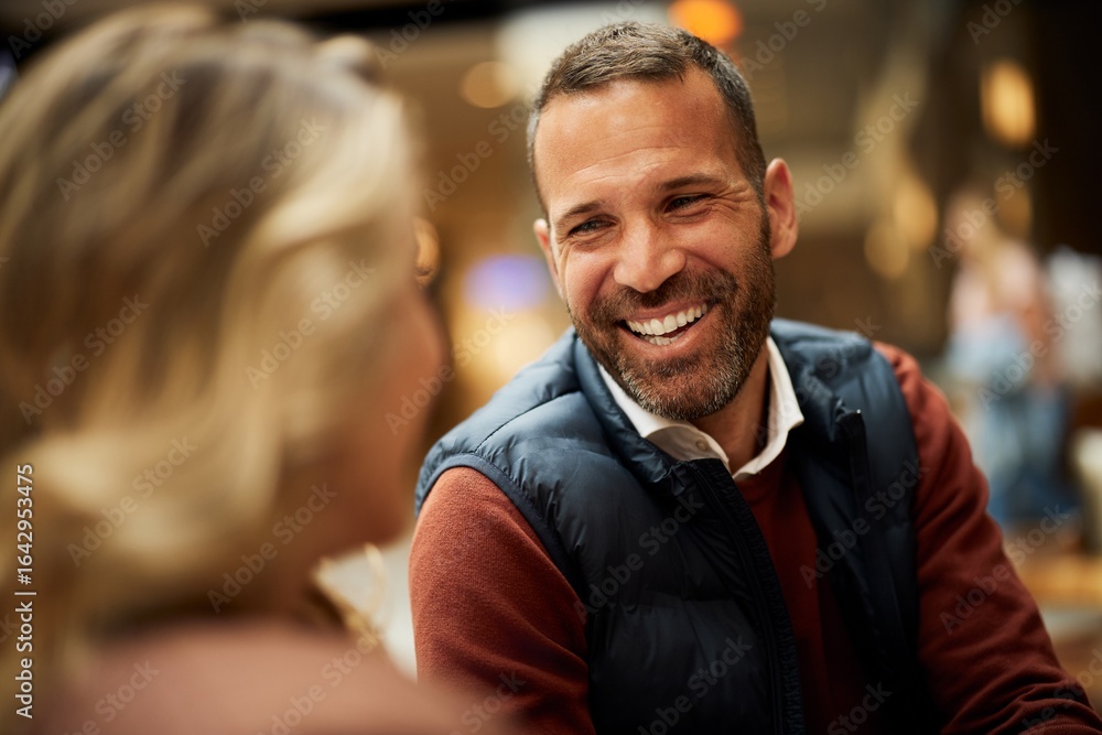 Obraz premium Smiling Man Engaging in Lively Conversation with a Woman at a Cafe