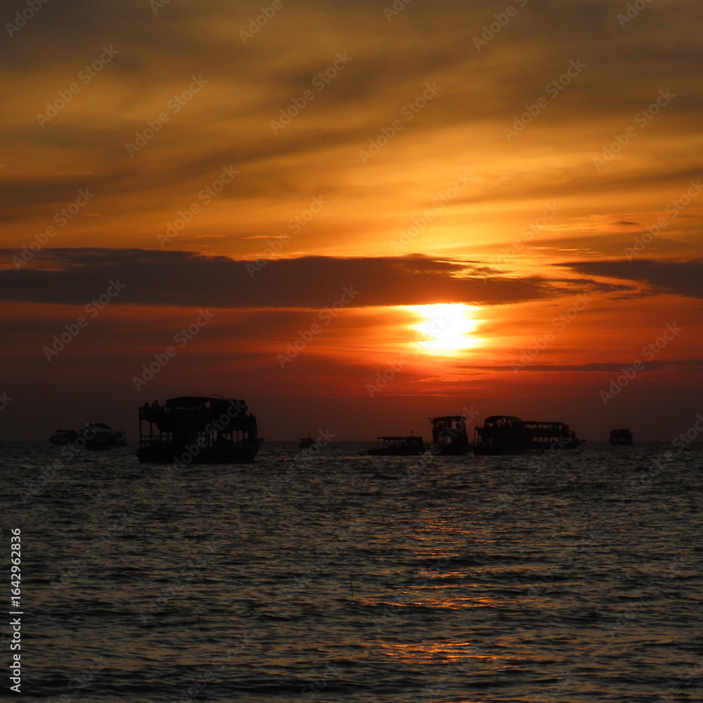 Fototapeta premium bright red sunset with shadows of boats in the water